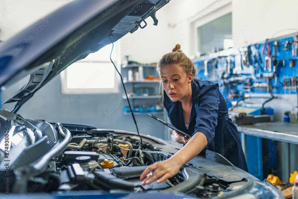 Mechanic working under the hood at the repair garage. Portrait of ...